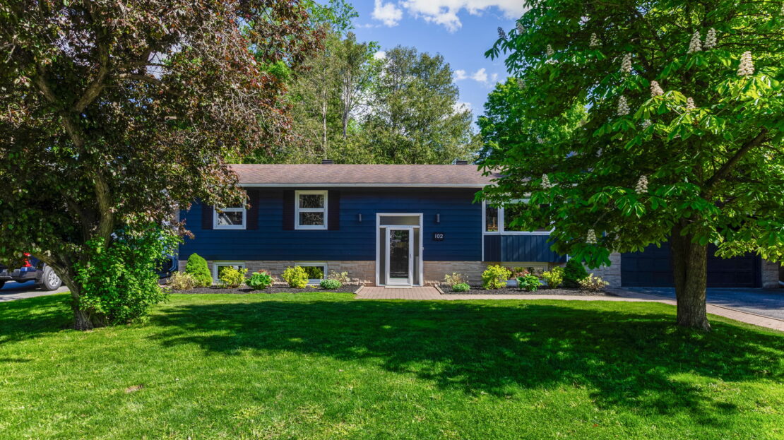 Front view of updated family home with interlock driveway and landscaped yard at 102 Coburn Avenue in Ottawa